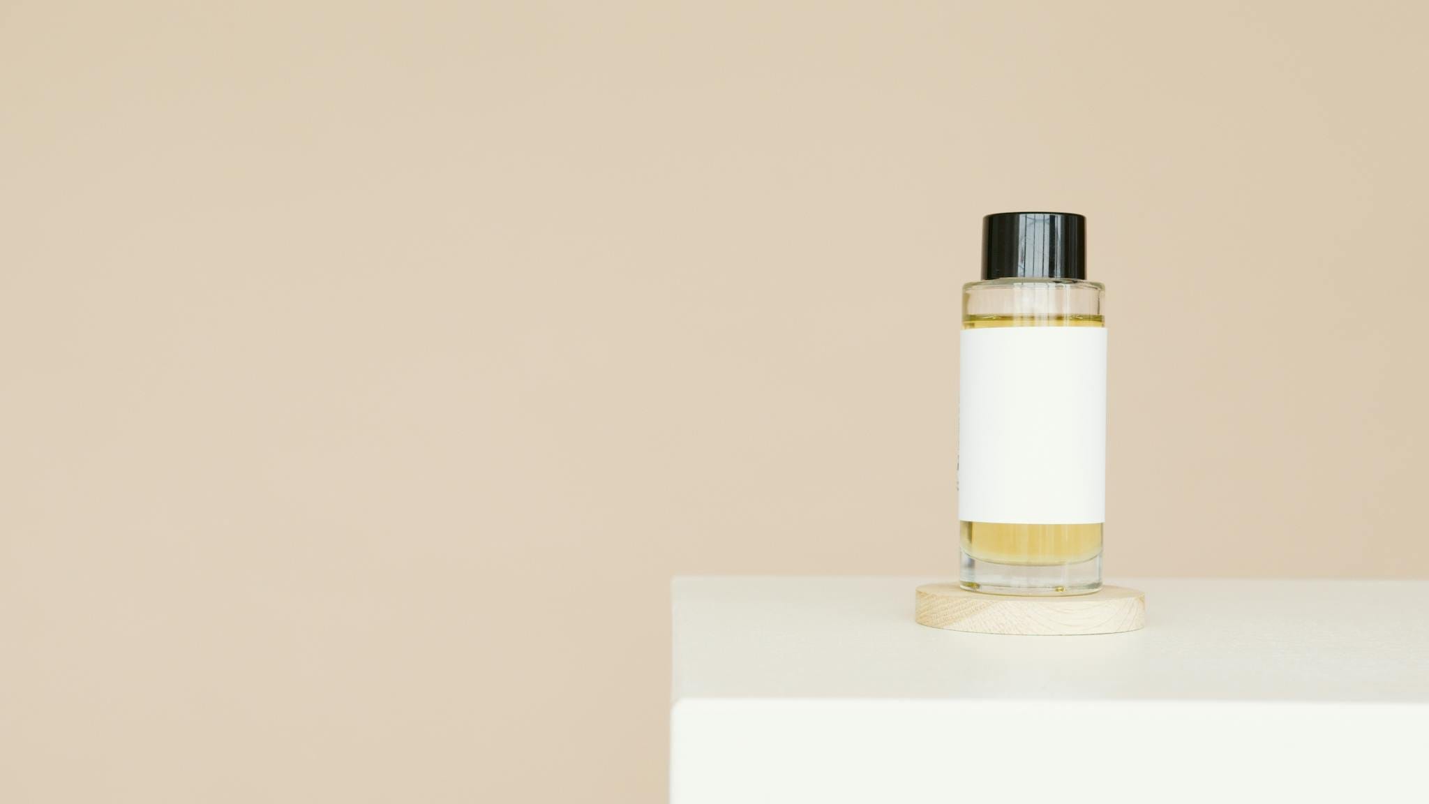 A sleek cosmetic bottle with blank label on a clean white platform against a neutral background.